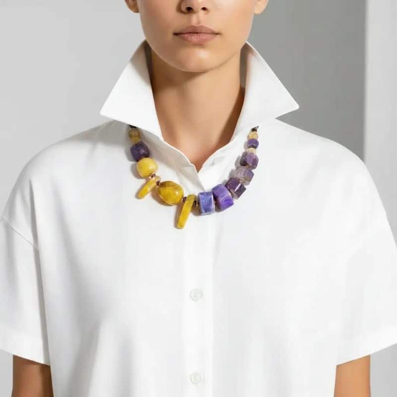 Natural Stone Necklace 0369009. Radiate confidence and individuality with this one-of-a-kind Purple & Yellow Agate Necklace, a celebration of natural beauty and vivid design. Featuring a striking combination of deep purple and bright yellow agate stones, this handcrafted natural stone necklace creates an elegant contrast that catches the eye and uplifts the spirit. Each stone is carefully selected and arranged to maximize visual impact, resulting in a festive and sophisticated necklace. Measuring 18 inches in length, the stone necklace rests gracefully along the neckline, perfectly proportioned for everyday elegance or special occasions. The natural agate stones, rich with unique patterns and translucent depth, tell their own story. Agate was first discovered by the ancient Greek philosopher Theophrastus in the Dirillo River of Sicily—then known as Acate—and has long been valued for its grounding energy and timeless beauty. This stunning natural stone necklace is perfect for adding a touch of elegance to any outfit. This piece isn’t just jewelry—it’s wearable history and vibrant artistry in one. With only a single necklace available, you’ll be wearing a truly exclusive treasure that reflects your distinctive style. Whether you choose it for its vibrant palette, its historical connection, or its rare availability, this necklace is sure to become a beloved highlight in any collection. Bold, radiant, and utterly unique.