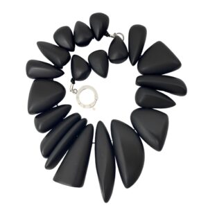 Bold black Dior necklace featuring large matte geometric beads in tapered teardrop shapes with a silver circular clasp engraved with the brand name, arranged in a sculptural, modern design.