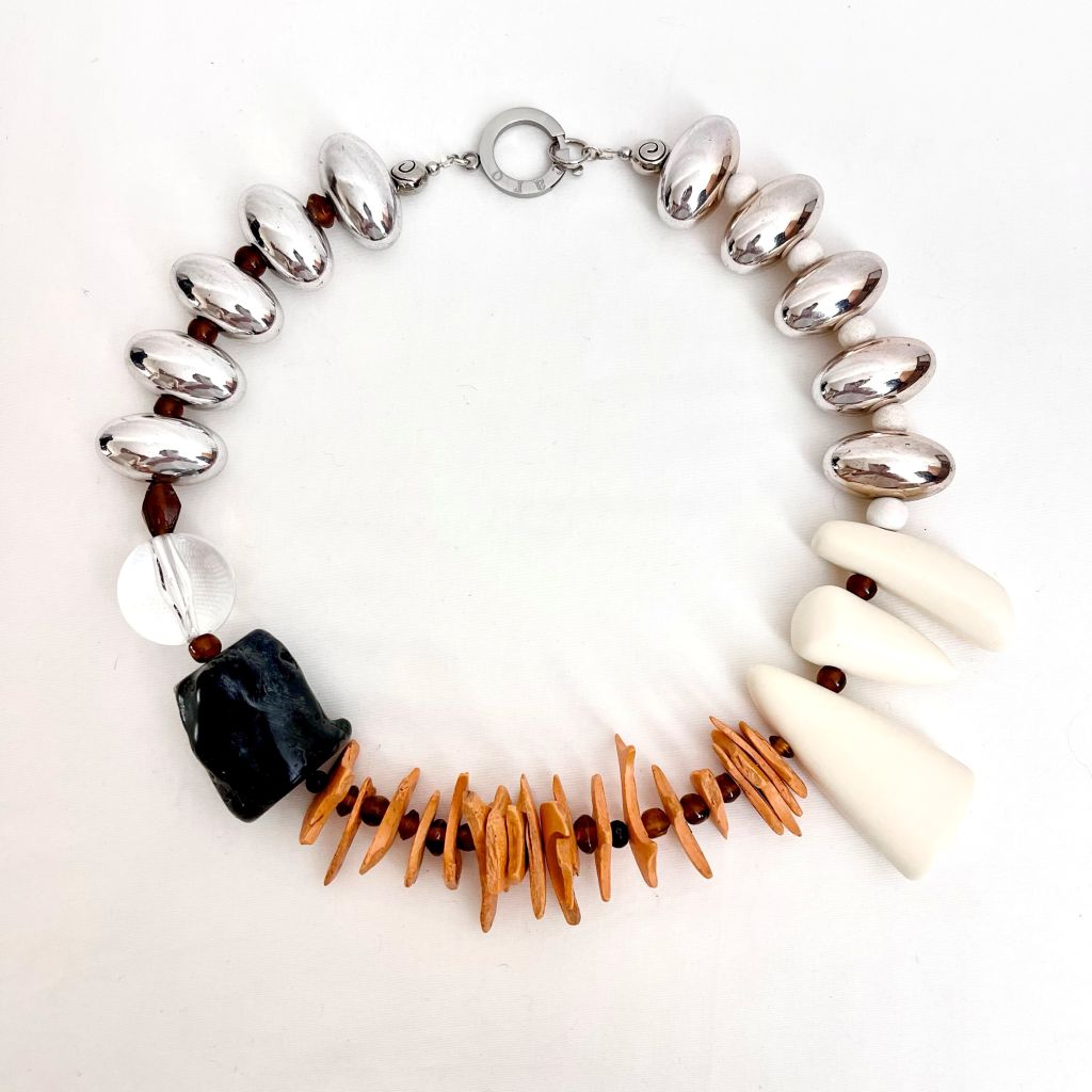 Handcrafted coconut shell necklace displayed on a white background, featuring polished brown, tan, and cream beads with mixed organic shapes and textures, creating a natural, tropical aesthetic.