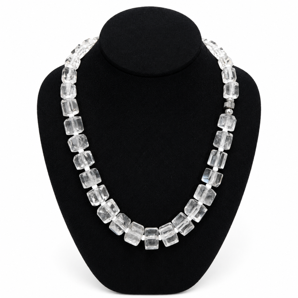 Elegant clear crystal necklace featuring rectangular faceted beads displayed on a black jewelry bust, highlighting the geometric design and luminous transparency of each bead.