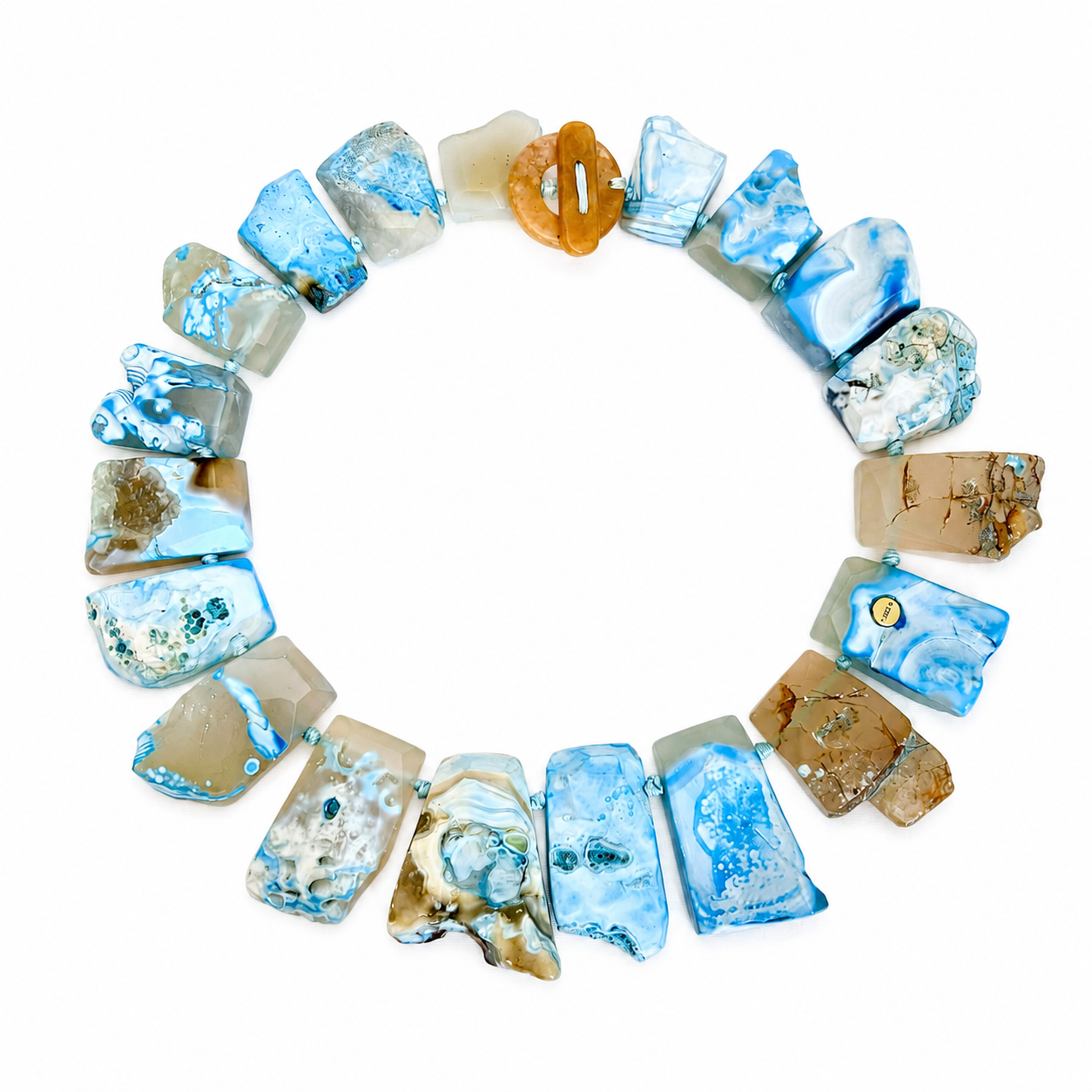 Handcrafted necklace featuring irregular polished blue agate stones in shades of sky blue, beige, and cream, accented with a warm amber clasp. The design highlights organic texture and artisanal craftsmanship.