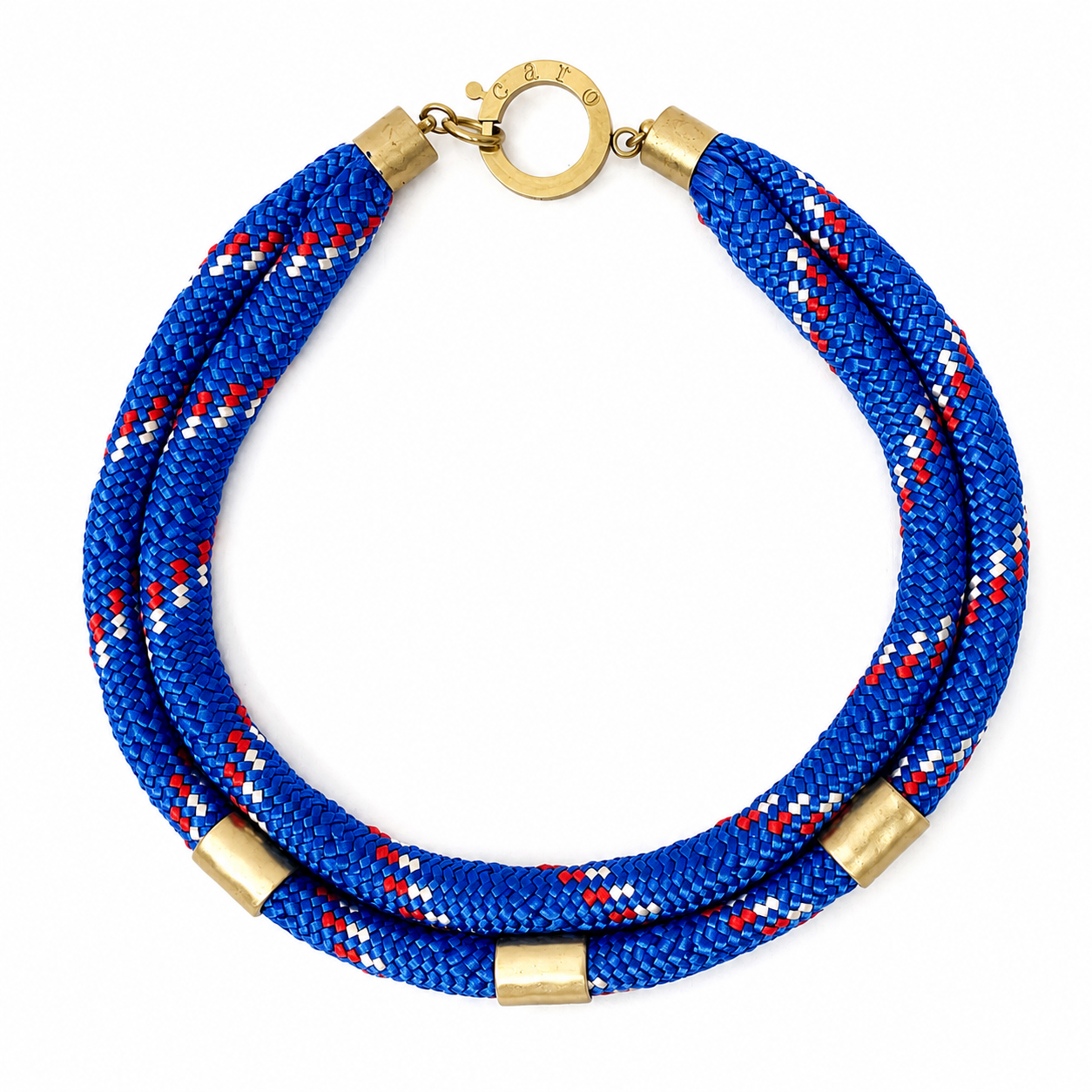 Handcrafted double‑strand necklace featuring braided rope in blue, red, and white tones with gold cylindrical accents and a circular gold clasp engraved “Caro.” The design highlights sporty sophistication and layered craftsmanship.
