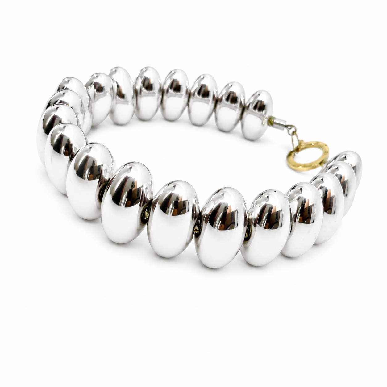 Handcrafted choker necklace featuring polished silver‑tone oval beads arranged in a circular design with a gold‑tone clasp. The reflective surface highlights sculptural craftsmanship and modern elegance.