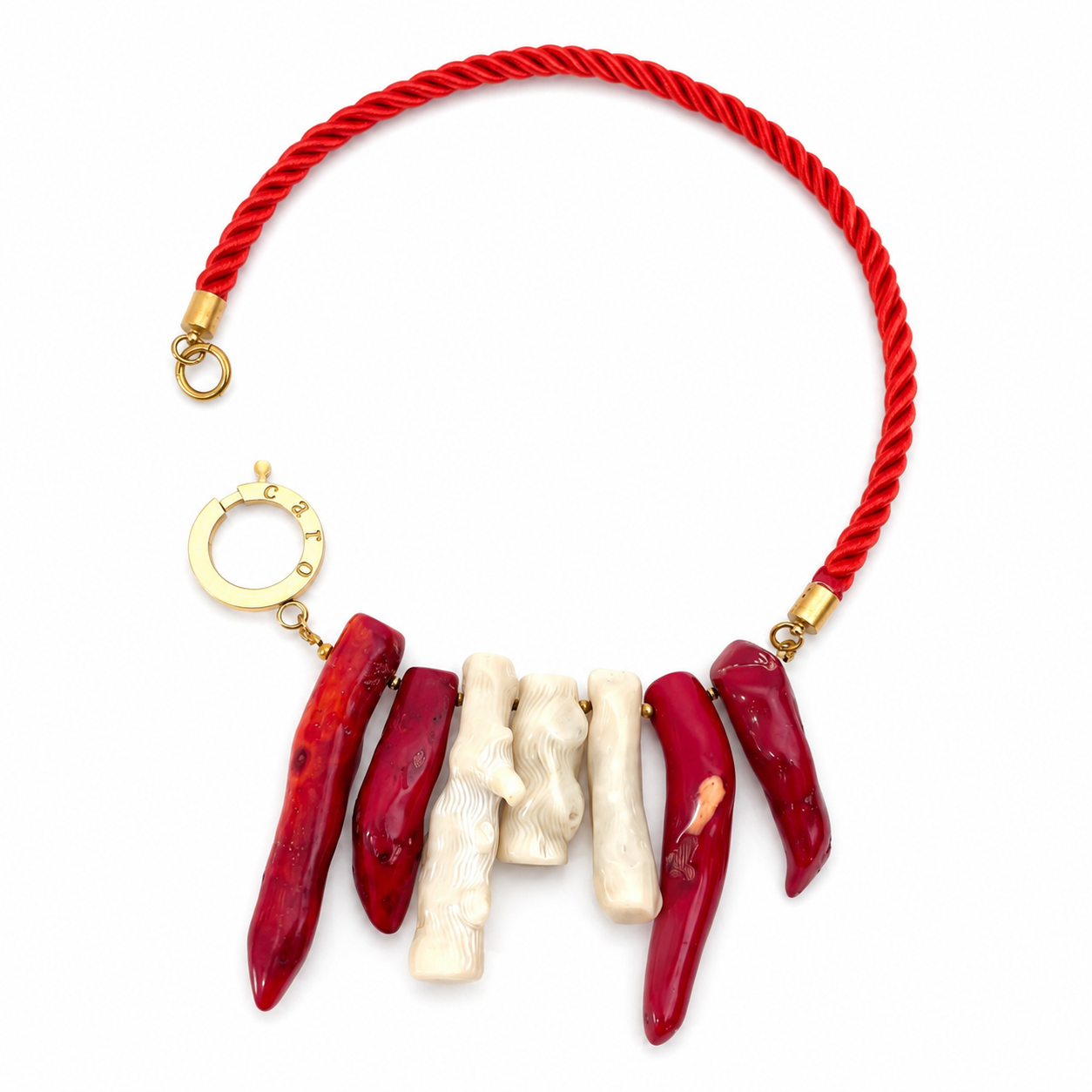Handcrafted necklace featuring a twisted red silk cord with alternating red and ivory coral stones, accented by gold‑tone fittings and a circular clasp engraved “Caro.” The design highlights organic texture and vibrant coastal elegance.