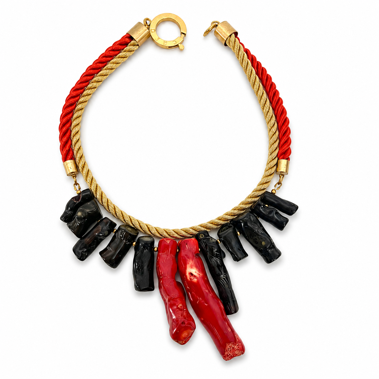 Handcrafted necklace featuring a twisted gold and red silk cord adorned with irregular natural coral stones in red and black, finished with a circular gold clasp engraved “Caro.” The design highlights organic texture and refined craftsmanship.