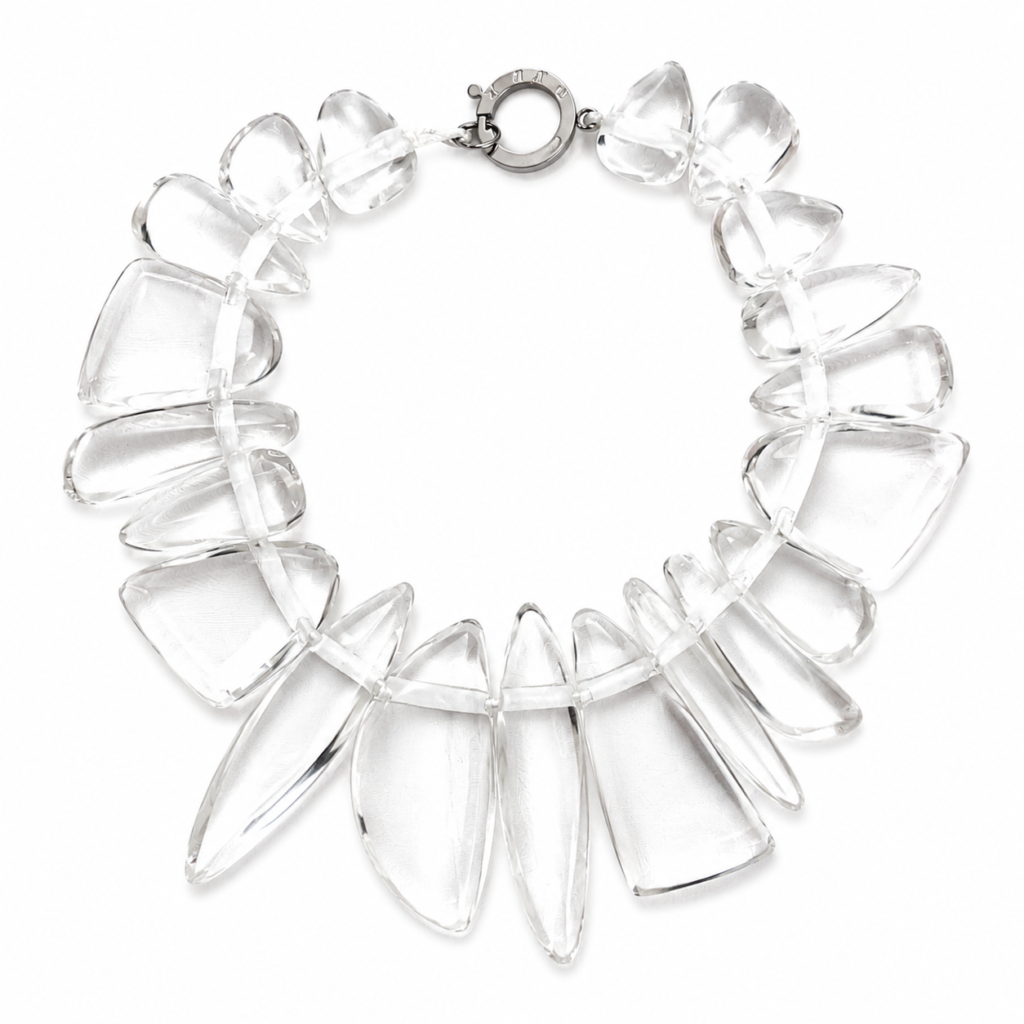 Handcrafted necklace featuring irregular clear acrylic beads arranged in a circular design with a silver‑tone clasp engraved “Caro.” The transparent beads create an ice‑like effect, highlighting modern craftsmanship and minimalist elegance.