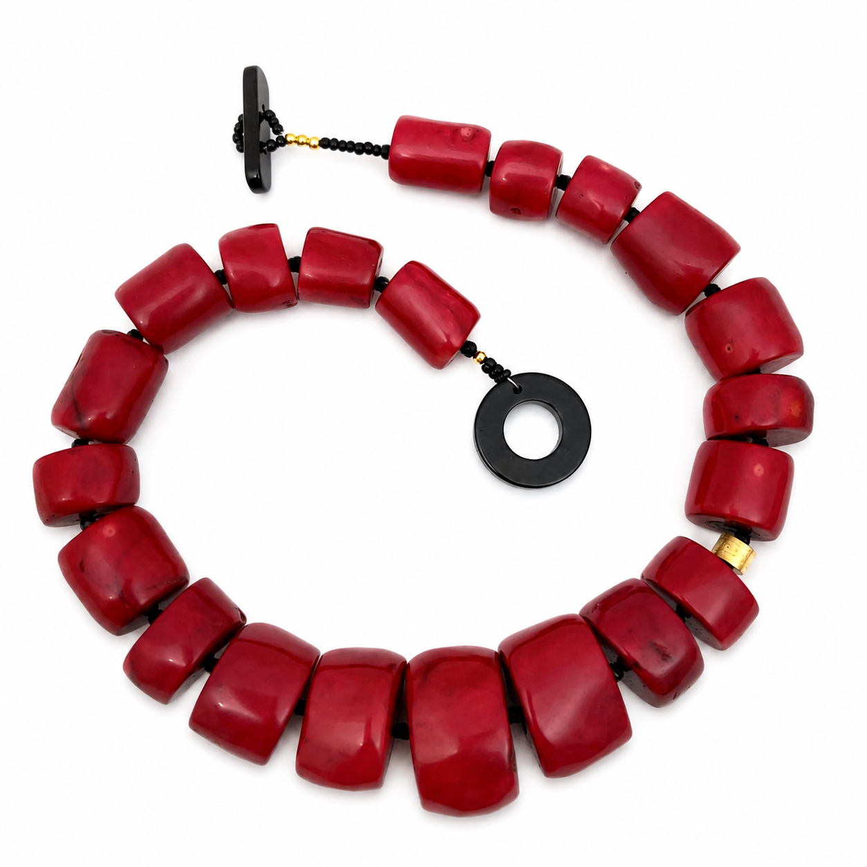Handcrafted necklace featuring smooth red beads and a polished black stone toggle clasp. The design highlights bold color contrast and refined craftsmanship.