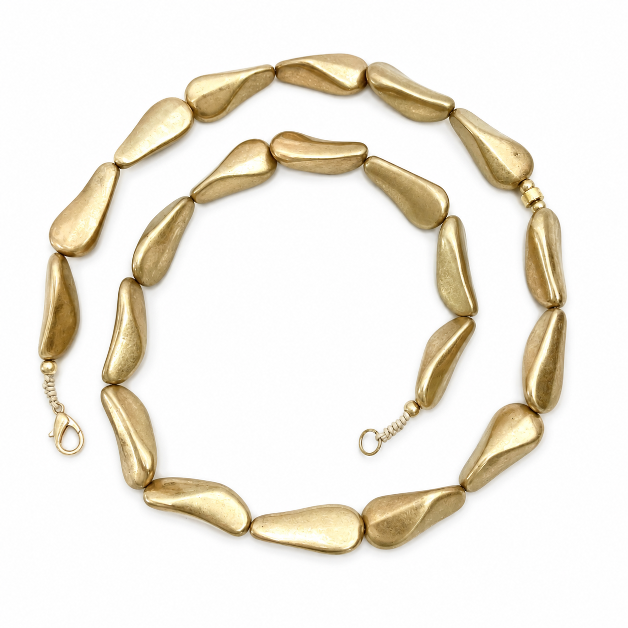 Handcrafted necklace featuring irregular elongated matte gold metal beads arranged in a long, elegant strand. The soft gold hue and distinctive bead shapes create a modern, sculptural look.
