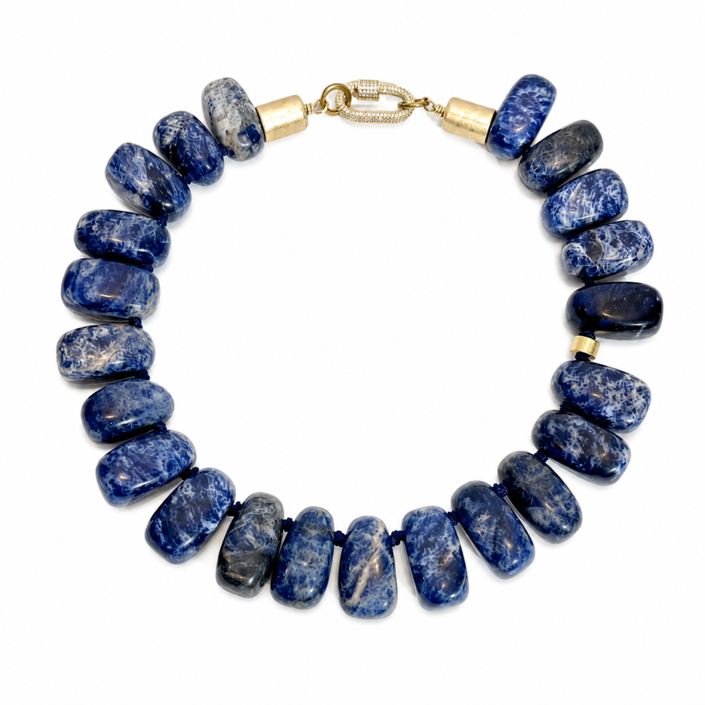 Handcrafted necklace featuring large polished Sodalite stones in deep royal blue with white marbling, strung on a blue cord with gold‑tone clasp.