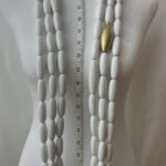 A minimalist style of three strands of white oval beads