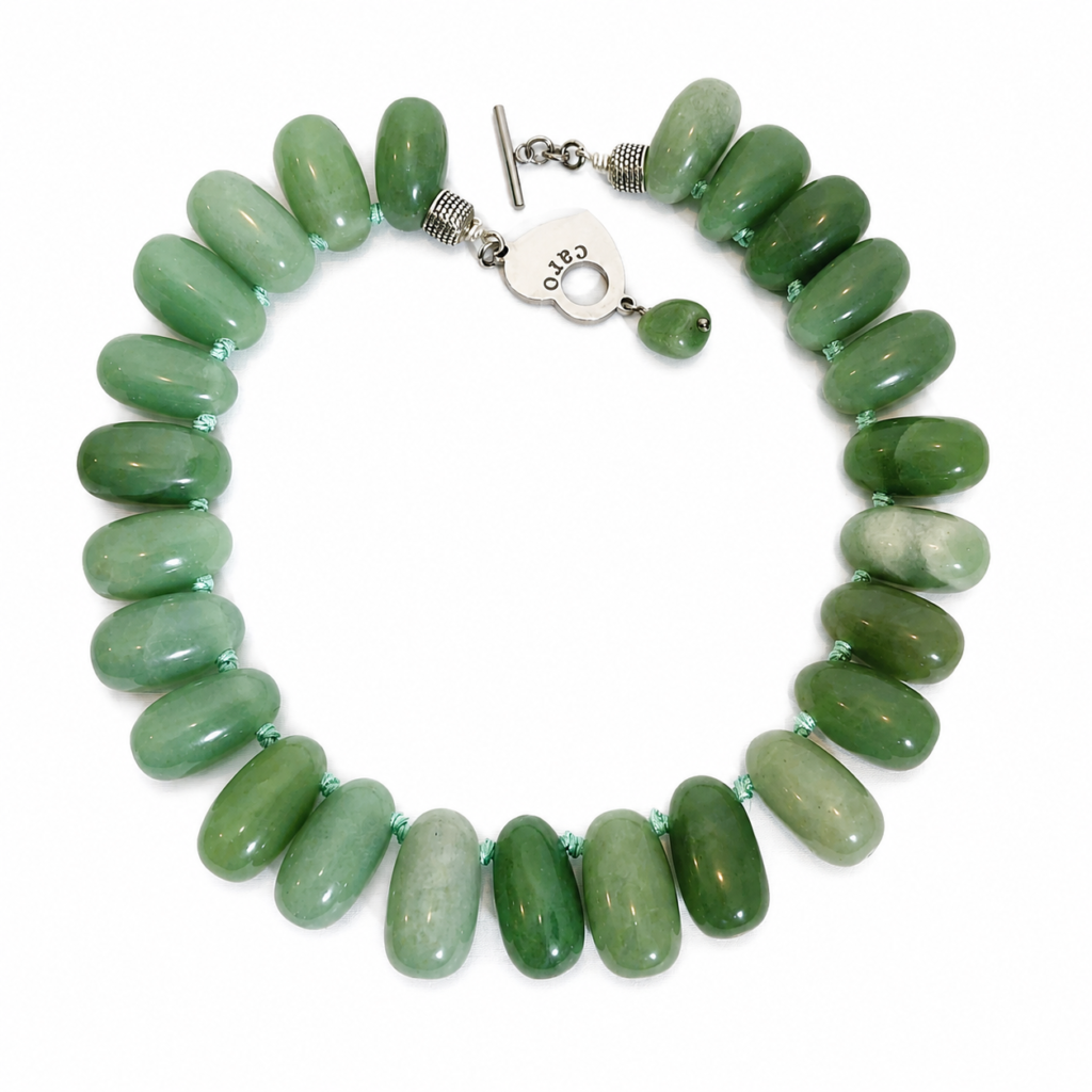 Handcrafted necklace featuring large polished green Aventurine beads with subtle Fuchsite shimmer, strung on a light green cord with a silver toggle clasp engraved “Caro.” Displayed on a white background.