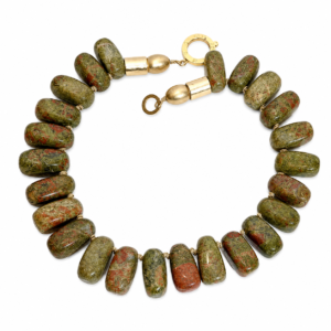 Handcrafted necklace featuring large polished Unakite beads in green and reddish tones, accented by matte gold cylindrical beads and a circular clasp engraved “Caro.” Displayed on a white background.