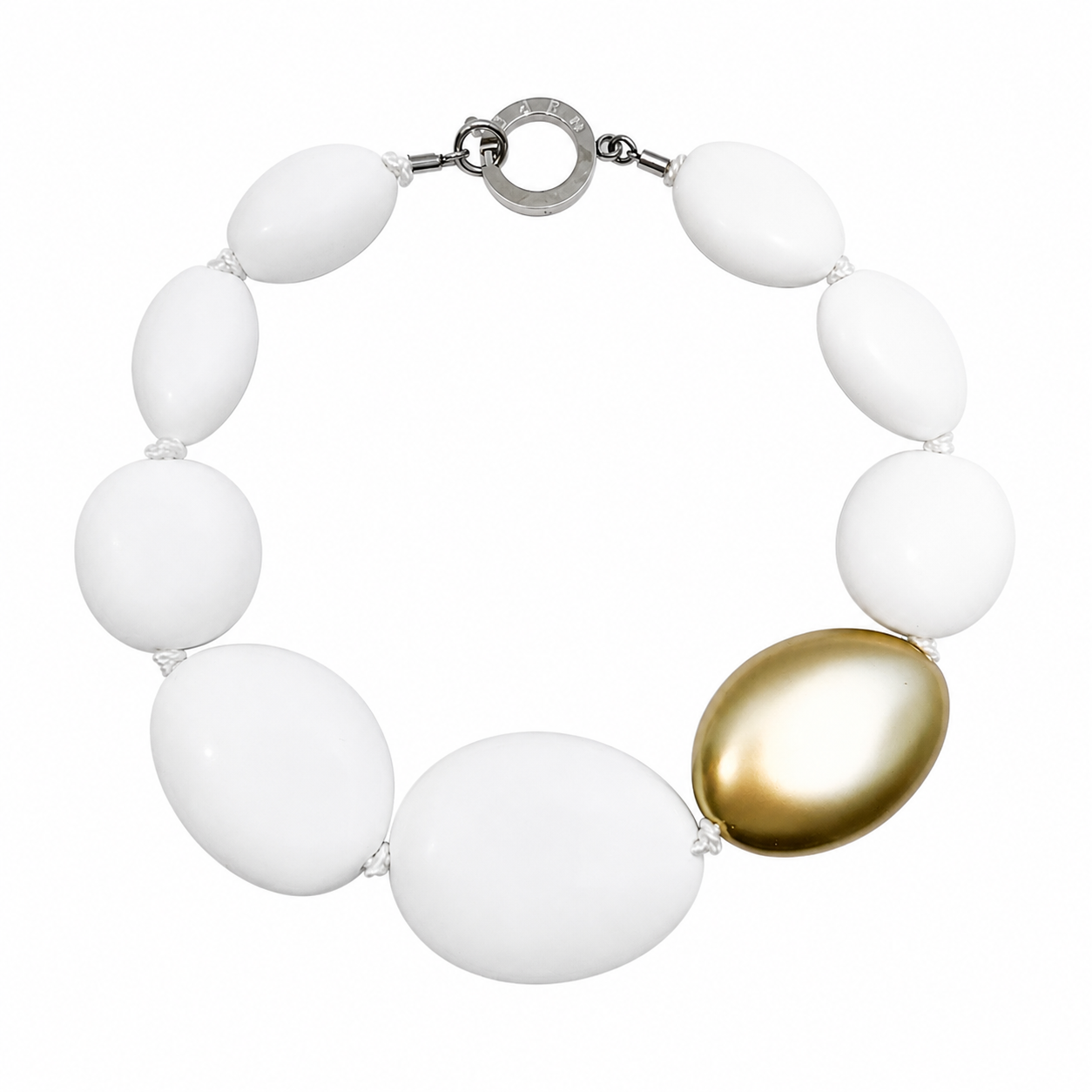 Handcrafted necklace featuring large matte white oval beads with one metallic gold accent bead, connected by a silver circular clasp engraved “Caro.” Displayed on a white background.