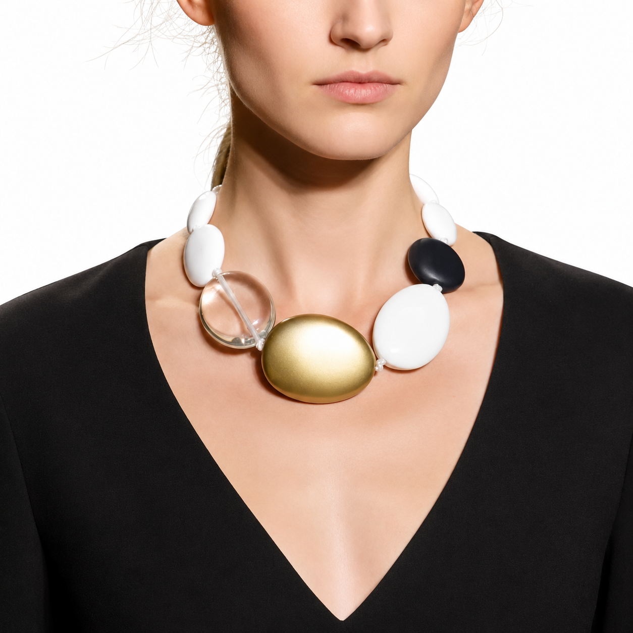 Model wearing a handcrafted multi‑accent oval bead necklace featuring matte white, black, gold, and clear acrylic beads. Styled with a deep V‑neck black dress, showcasing the necklace’s bold, contemporary design and elegant contrast.