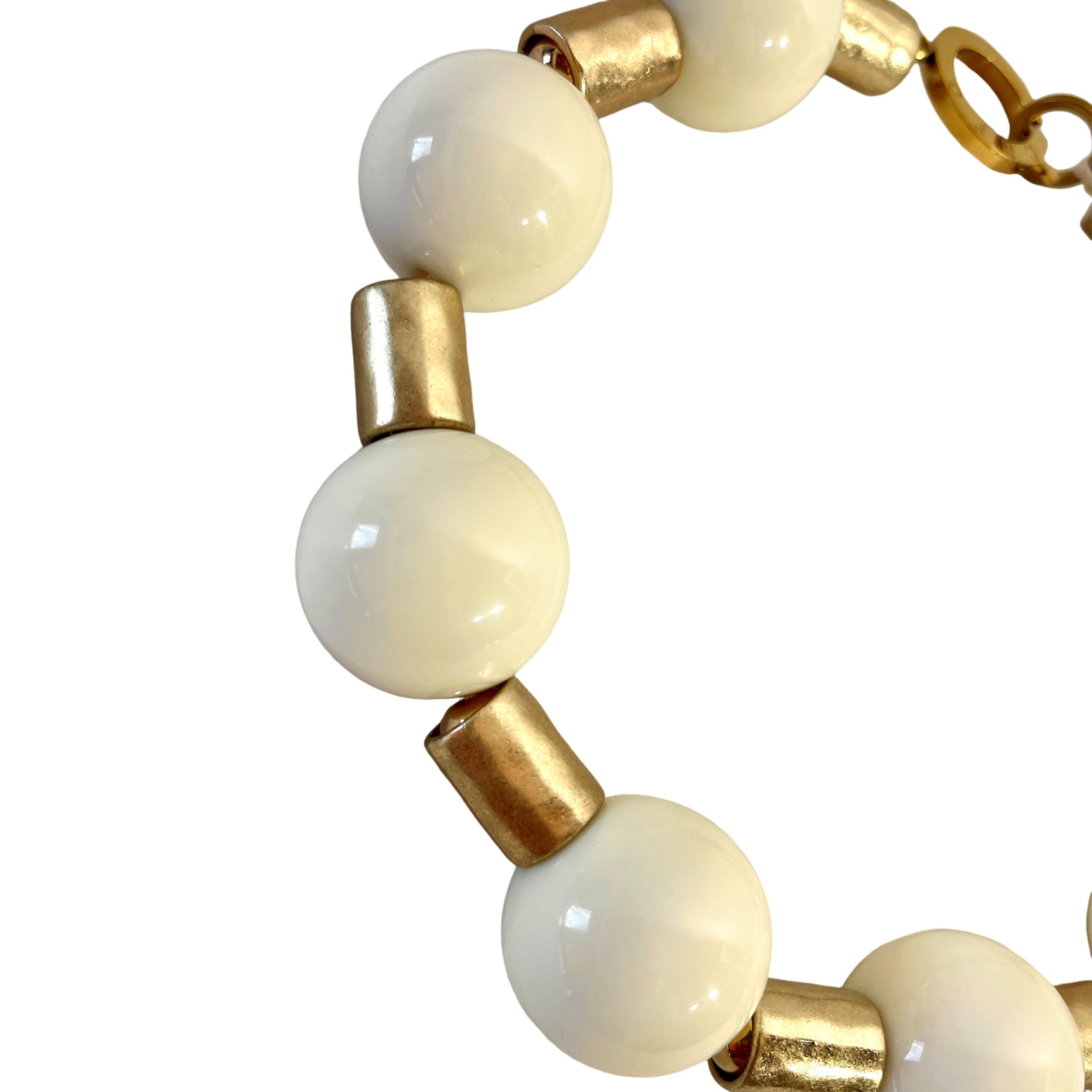 This elegant choker necklace blends classic charm with bold design, featuring large ivory-colored beads that radiate warmth and sophistication. Measuring 17 inches with an extender that allows up to 21 inches of length, it offers a customizable fit for comfort and versatility. Whether worn close to the neck or slightly lower, this piece adapts beautifully to your style. Between each smooth, ivory bead rests an antique gold cylindrical spacer, adding a touch of vintage refinement and enhancing the necklace’s visual rhythm. The contrast between the creamy tones and aged metallic accents creates a timeless aesthetic that complements both modern and traditional wardrobes. A sturdy lobster clasp ensures secure wear while echoing the necklace’s substantial character. The overall weight and balance make it a statement piece without overwhelming your look—perfect for layering or standing alone. Designed for those who appreciate thoughtful details, this necklace celebrates the richness of ivory hues and the allure of antique finishes. Whether you're dressing for a special occasion or elevating everyday attire, its graceful composition and adjustable length make it a go-to accessory. Let the soft glow of ivory and the textured gold spacers tell your story—one of elegance, strength, and enduring beauty.