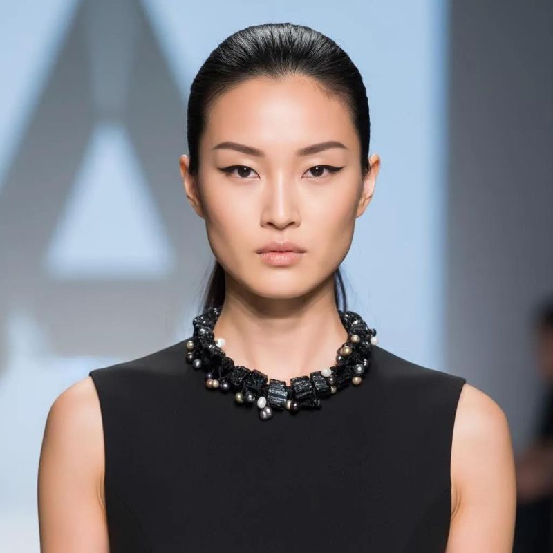 Black tourmaline and pearl statement necklace styled on a runway model wearing a sleeveless black dress.