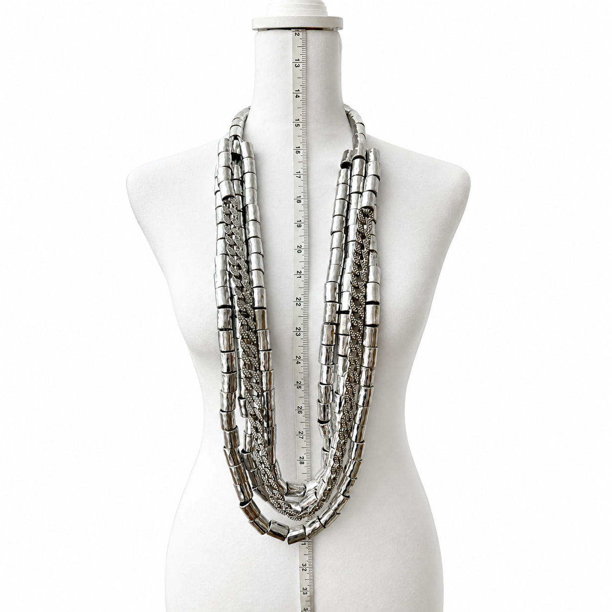 Mannequin displaying a layered silver necklace composed of cylindrical metallic beads and textured chains, measured vertically for length and drape.