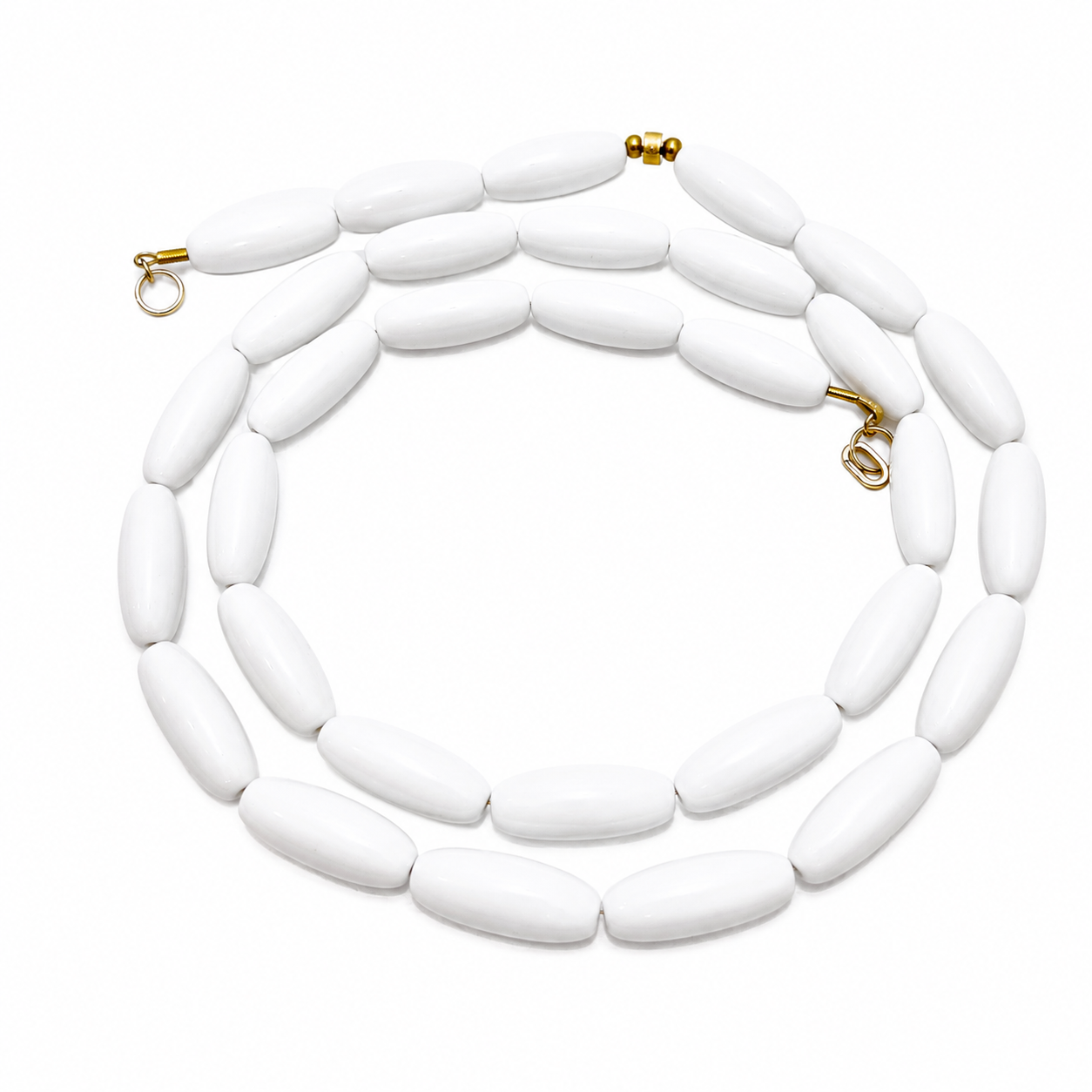 Long single‑strand necklace featuring smooth oval snow‑white beads with gold clasps, arranged in a circular pattern on a white background.