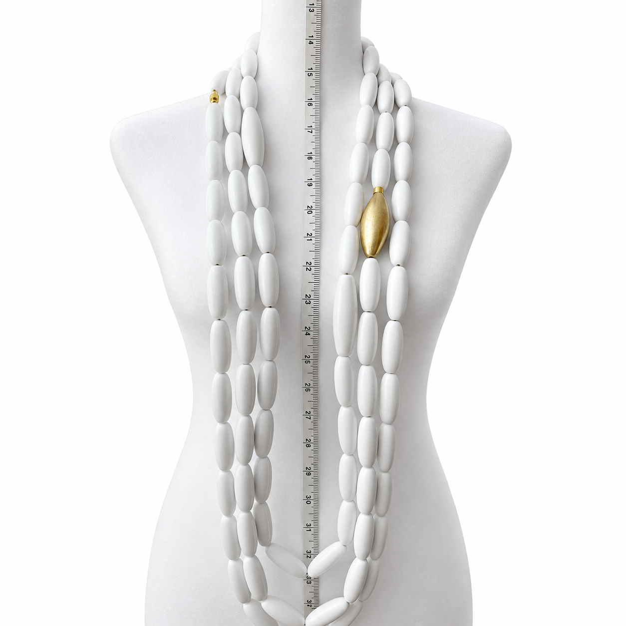 Mannequin displaying three extra‑long white bead necklaces with oval beads and one gold accent bead, measured vertically with a ruler for scale.