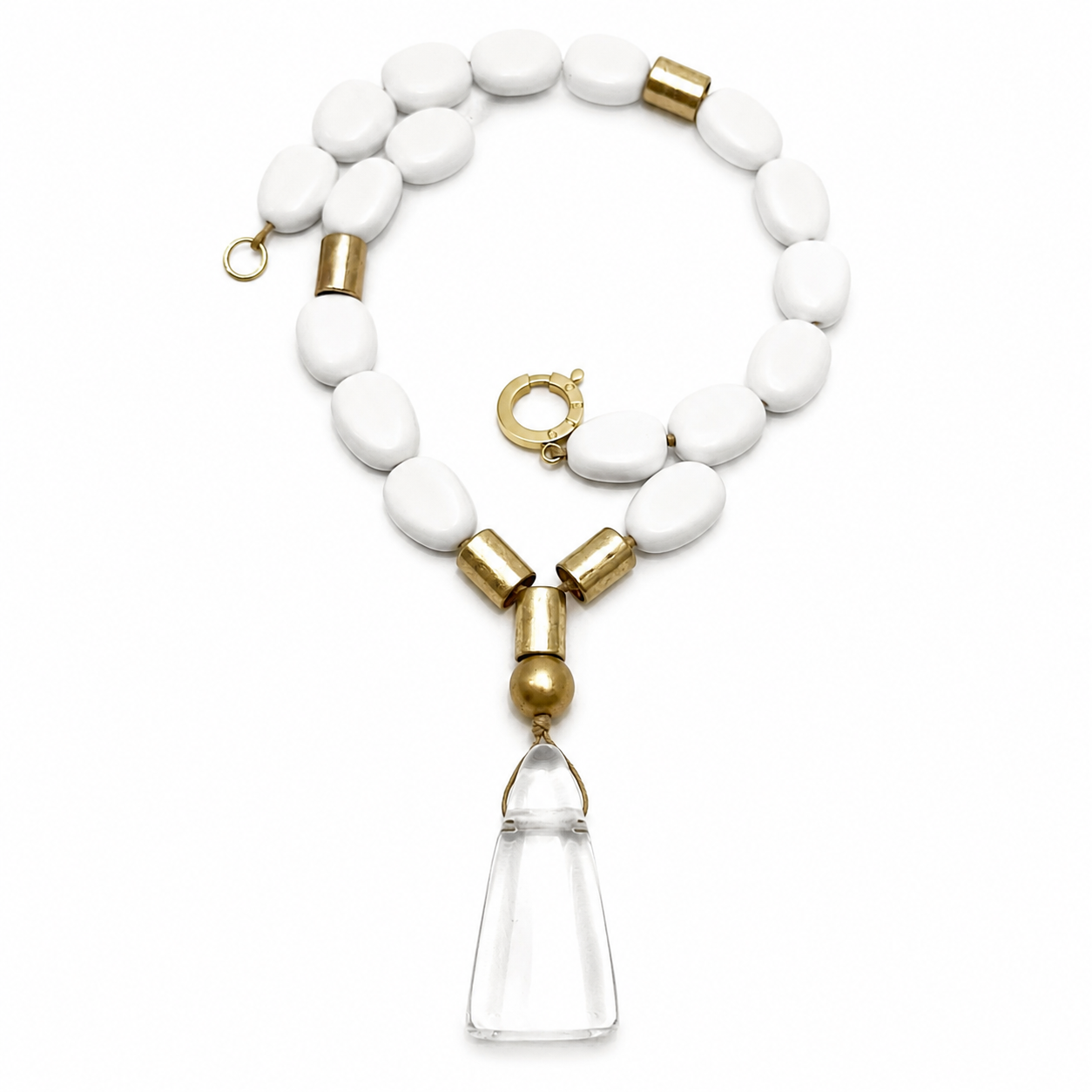 White bead necklace with gold cylindrical spacers and a large clear irregular pendant displayed on a white background.