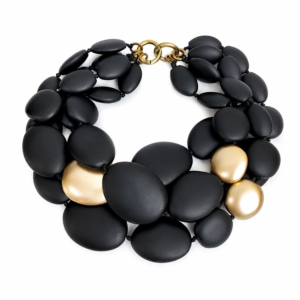 Multi‑strand necklace featuring matte black oval beads with gold accent beads, arranged in layered strands with brass circular clasps on a white background.