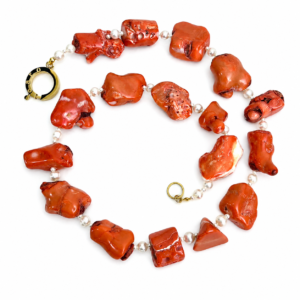 Long necklace featuring irregular raw orange coral beads interspersed with small round white pearls and gold clasp, displayed on a white background.