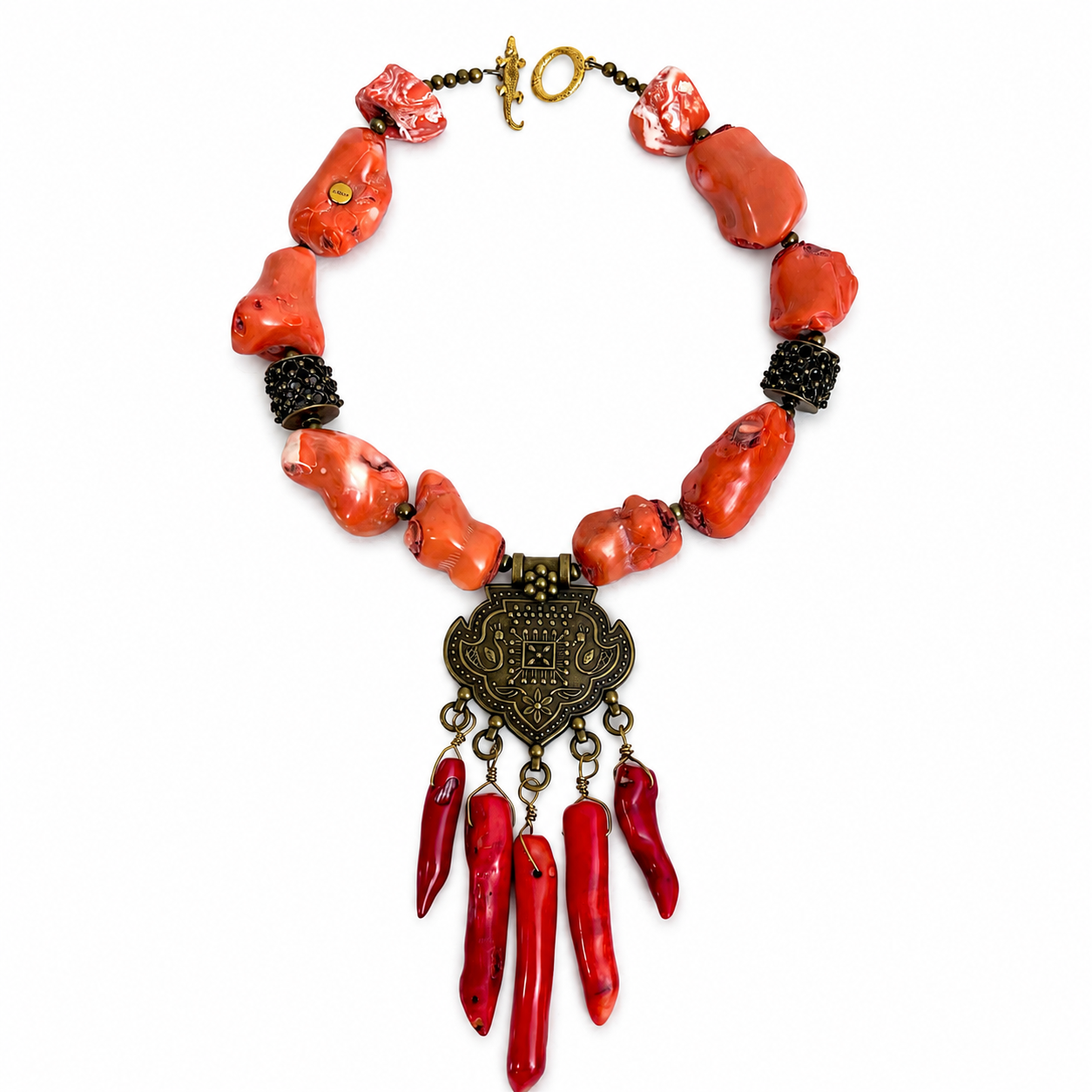 Handcrafted tribal necklace featuring irregular orange coral beads, dark metallic spacers, and an ornate brass pendant with engraved patterns and dangling red coral charms, displayed on a white background.