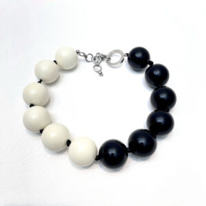 Black and ivory dual‑tone necklace featuring large glossy acrylic beads arranged in a half‑circle pattern with silver clasp, displayed on a white background.