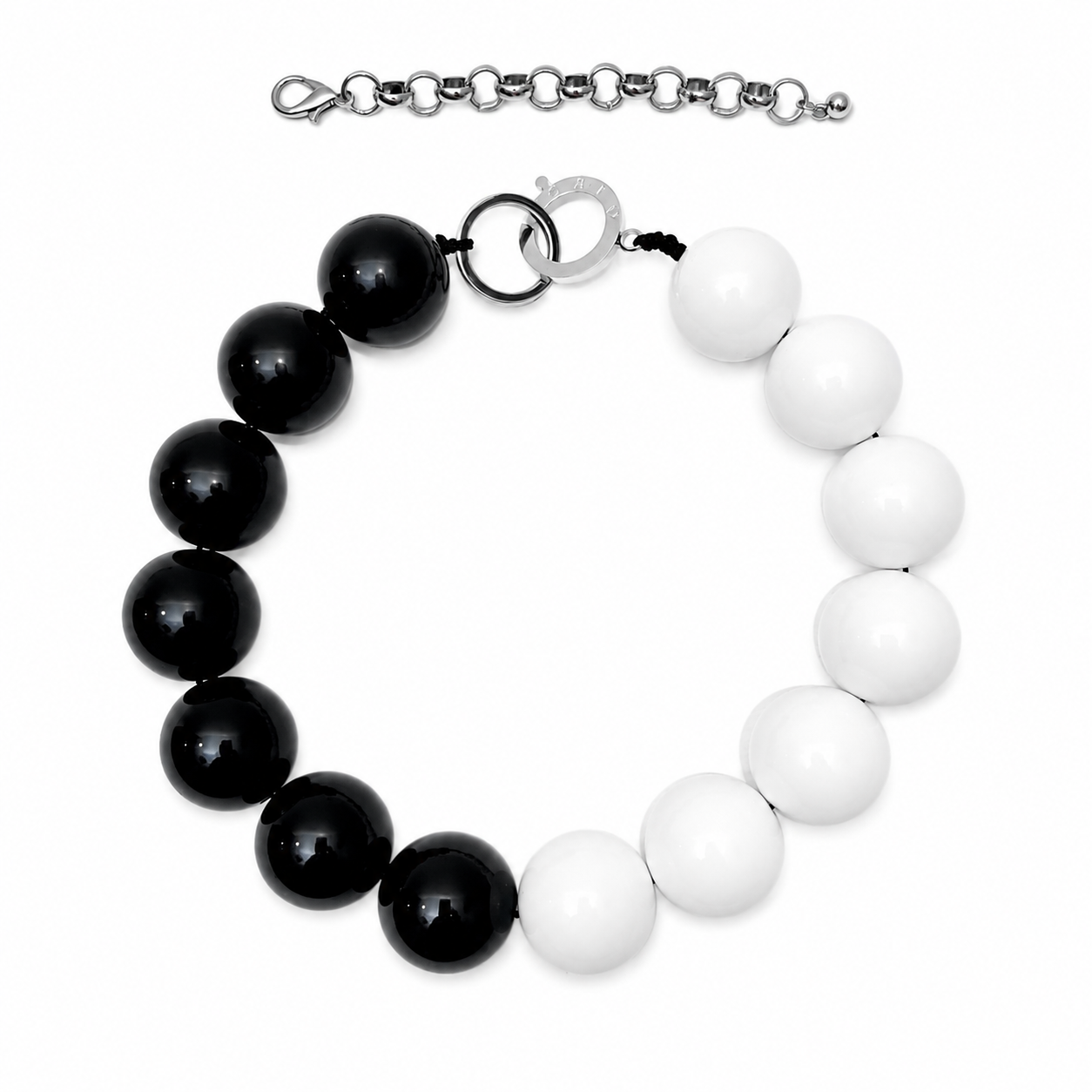 Black and white bead necklace featuring large glossy spherical beads arranged in a half‑circle pattern with silver clasp and detachable extender chain, displayed on a white background.
