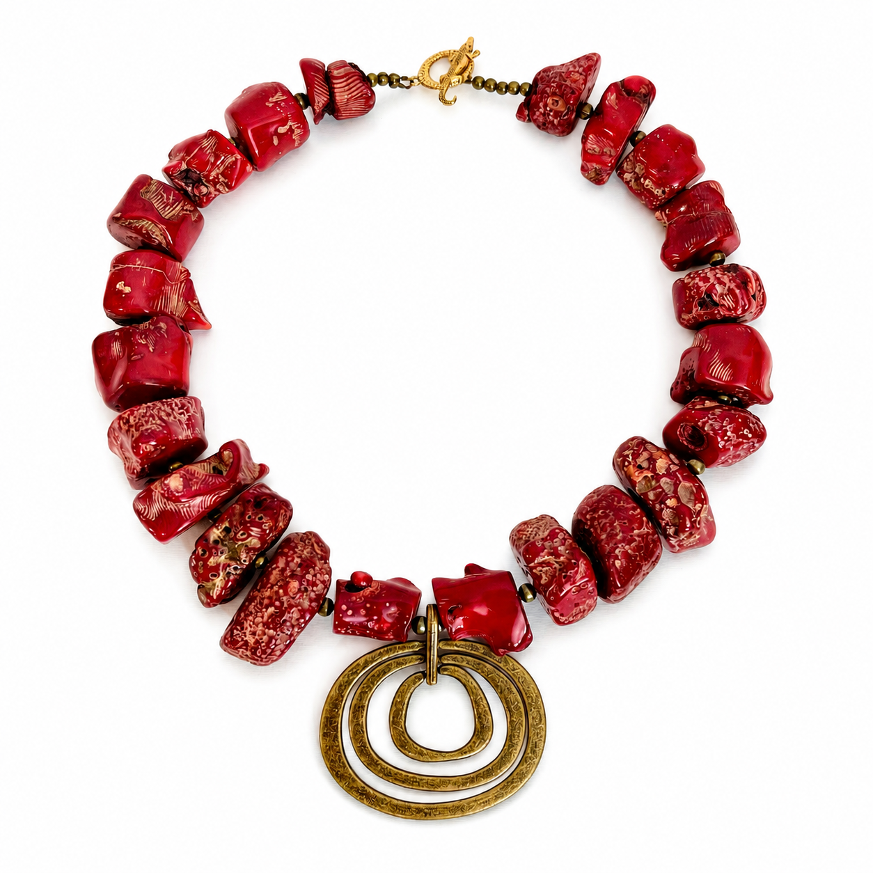 Handcrafted necklace featuring irregular red coral beads with natural texture and a brass pendant of three concentric rings, displayed on a white background.