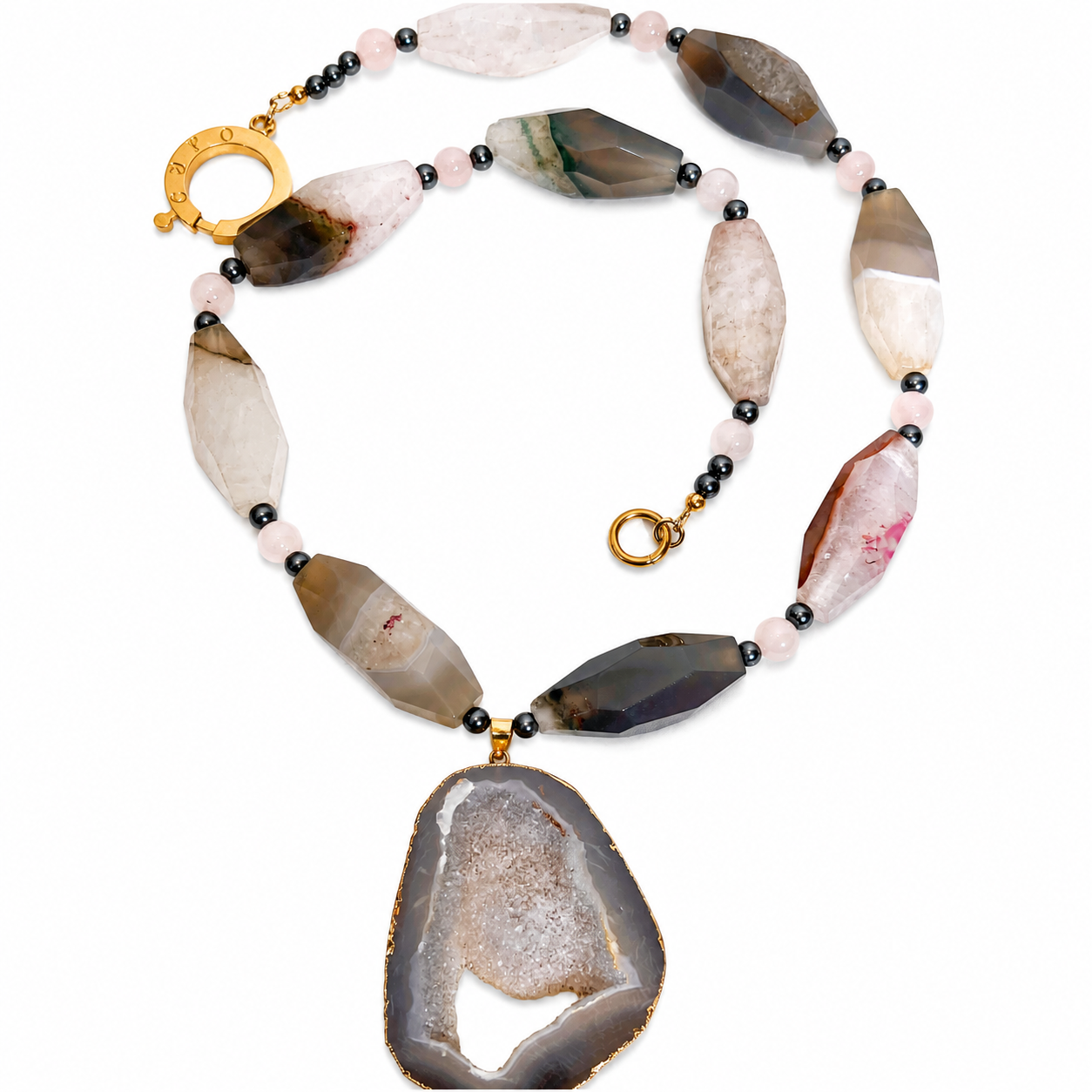 Handcrafted necklace featuring faceted gray and white semi‑precious stones interspersed with pink quartz and black pearl beads, centered by a large sliced gray agate pendant with a crystalline core and gold rim, displayed on a white background.