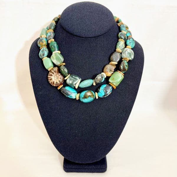 Elevate your jewelry collection with a necklace that blends timeless beauty and the wonders of Earth’s history. This captivating two-strand piece features genuine Aventurine and Turquoise beads, artfully arranged to showcase their natural colors and tranquil energy. The rich greens of Aventurine and the soothing blues of Turquoise harmonize effortlessly, creating a visual rhythm that’s both grounding and refreshing. At the heart of this design lies its most distinctive element: authentic Ammonite fossils, formed between 66 and 200 million years ago during the Jurassic and Cretaceous eras. Each fossil bears its own pattern, hue, and texture—offering a rare glimpse into nature’s prehistoric artistry. These ancient stones add depth and character, transforming the necklace into a wearable artifact with an organic elegance that can’t be replicated. Crafted to fit comfortably, the necklace measures 16.5 inches, with an extension chain that adjusts up to 20 inches—ideal for versatile styling and all-day wear. Whether worn solo as a statement piece or layered for a bohemian look, it speaks to those who admire both natural history and refined craftsmanship. This necklace isn’t just jewelry—it’s a celebration of nature’s resilience and the timeless beauty of authentic materials.