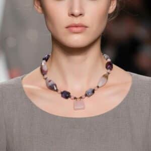 Delicate yet expressive, this sweet pink necklace is a refined celebration of soft tones and intricate natural beauty. Designed for those who appreciate quiet elegance, it features the captivating Botswana Agate—renowned for its subtle banding and harmonious blend of pink and gray hues. These calming tones are mirrored in the pairing of blush-pink Quartz and cool gray Pearls, lending the necklace an air of romantic sophistication. Though petite in size, the pink necklace offers a wealth of detail. The Botswana Agate’s intricate patterns provide visual depth, while each element contributes texture and grace. A charming pink Agate handbag pendant serves as a playful accent that elevates the minimalist silhouette. Adding a final note of luxury, a striking gold charm completes the design with a polished touch. Measuring with comfort and style in mind, this pink necklace is ideal for layering or wearing solo to draw subtle attention. It’s the perfect statement for soft-spoken fashionistas who favor expressive accessories with personality and intention. Whether gifted or chosen for oneself, this necklace brings together modern sensibility and natural artistry in one graceful composition—proof that small treasures often carry the biggest stories.