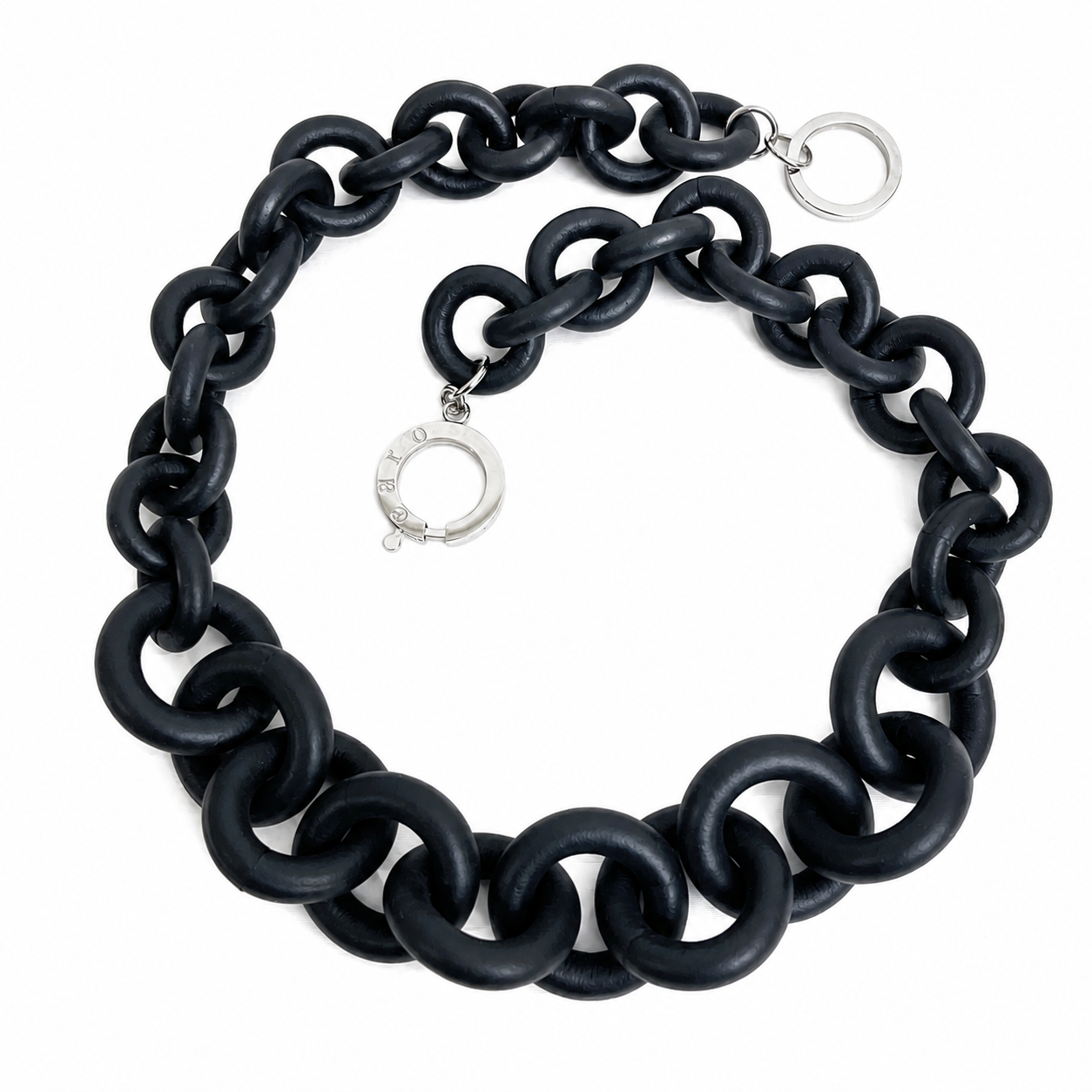 Black chain necklace composed of large interlocking matte rubber links with silver metal ring clasps engraved “Caro,” displayed on a white background.