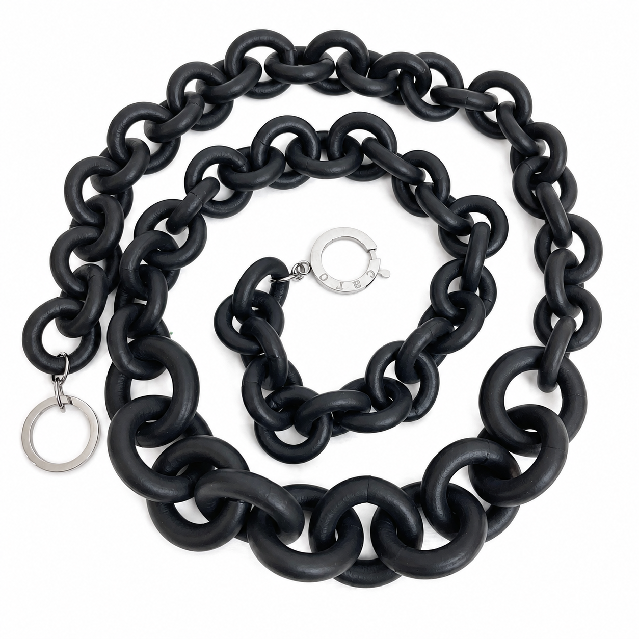 Chunky black chain necklace composed of large matte rubber links with silver metal ring clasps engraved “Caro,” displayed on a white background. The necklace features oversized interlocking loops for a bold, sculptural look.