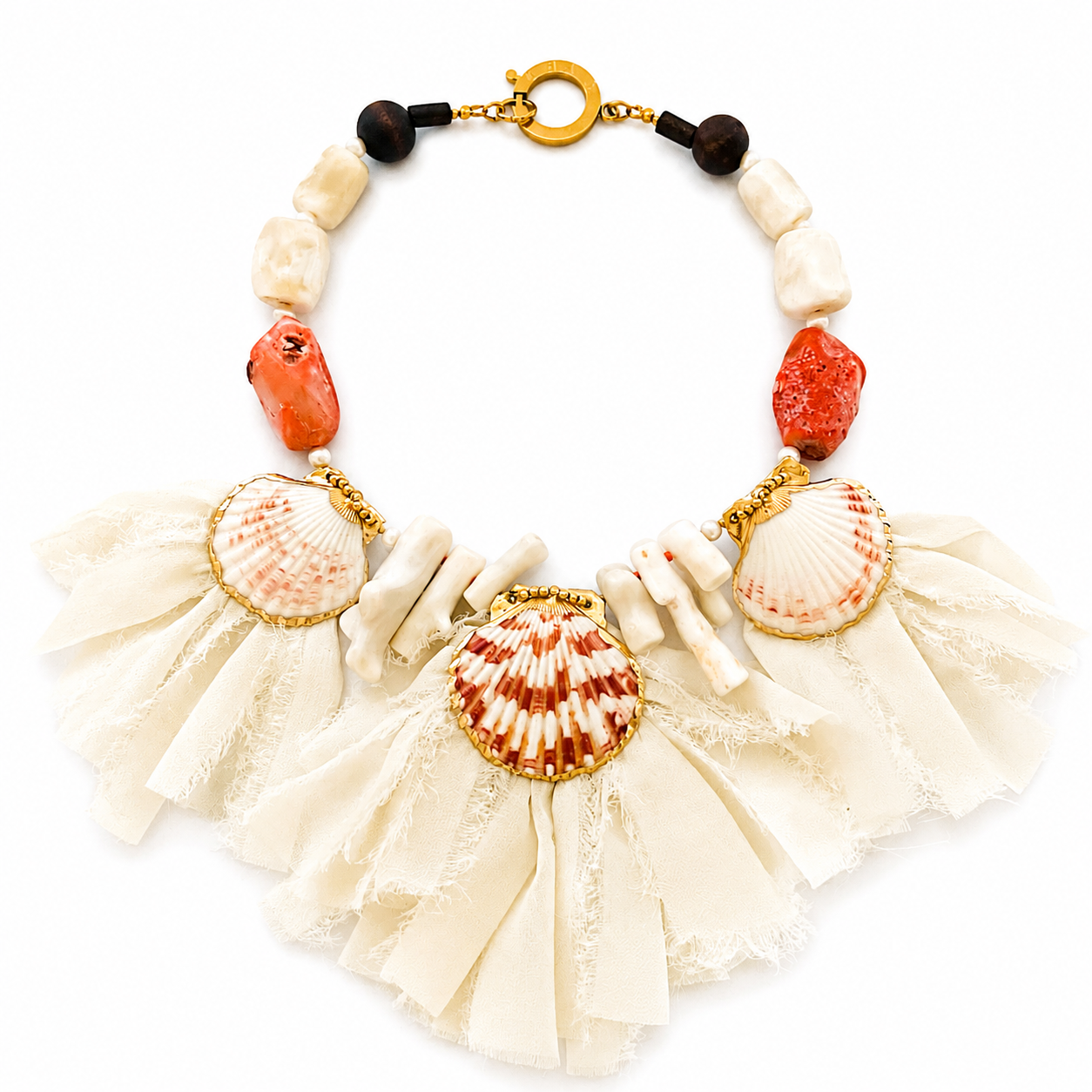 Handcrafted statement necklace featuring natural seashells, coral stones, and white coral branches arranged along a gold clasp. The design includes cream-colored fabric strips forming a soft fringe beneath the shells, creating a coastal-inspired, textured look.