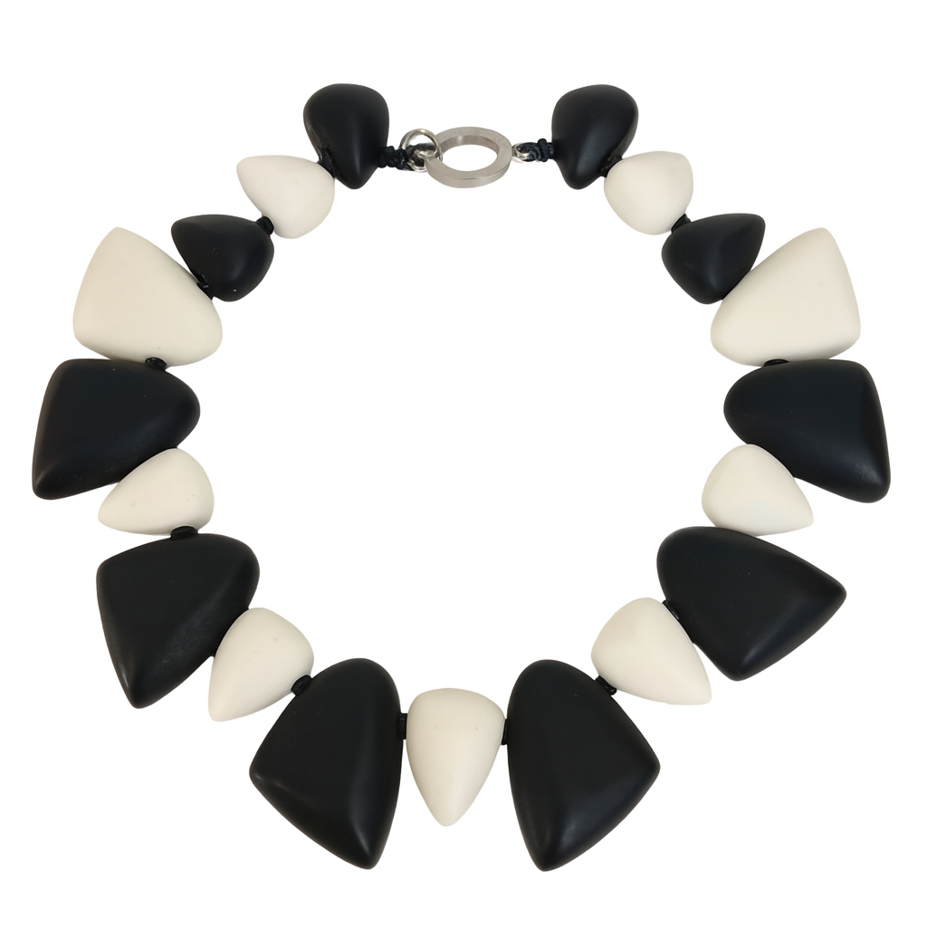 Chunky collar necklace made of alternating black and off-white triangular resin beads arranged symmetrically in a circular pattern, displayed on a white background.