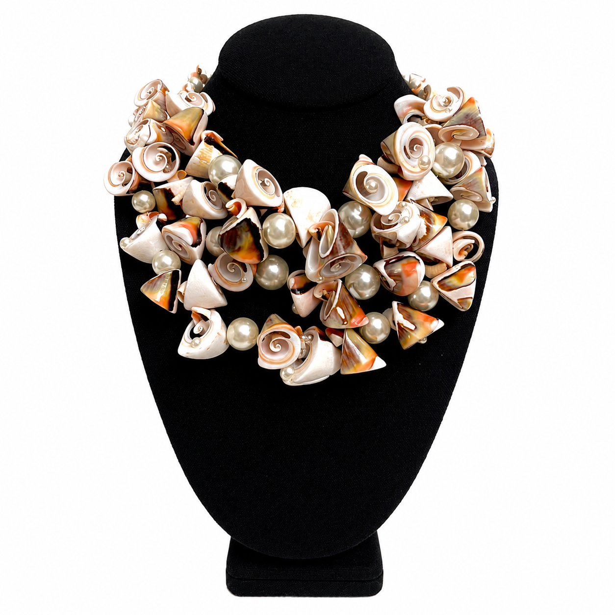 Handcrafted statement necklace featuring multiple spiral and cone-shaped seashells in shades of cream, beige, and pink, interspersed with pearl-like beads. The necklace has a gold-toned chain and clasp, creating a voluminous, layered design with organic elegance.