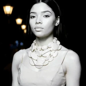 Graceful yet commanding, this exquisite double-strand necklace elevates your winter wardrobe with refined artistry and effortless style. Designed with versatility in mind, it transitions seamlessly between a single-strand silhouette—stretching up to 43 inches for an exotic, elongated look—and a layered choker effect that adds dramatic flair to turtlenecks and high-neck ensembles. Measuring 21 inches in its shorter form and weighing a wearable 22 oz, it offers both visual impact and lightweight comfort.  Wear it showing one strand, double it up to show a standard long necklace, or maximize its looks wearing an extra-long single strand that will reach beyond the knee length, for a dramatic effect with pants, or a long, flowy dress. The winter white is versatile during summer or winter.  The winter white palette exudes understated elegance, while oval-shaped beads shimmer with embedded rhinestones, catching the light with every movement. Their subtle sparkle brings a festive touch to neutral tones, pairing beautifully with cashmere, wool, or sleek winter knits. Whether worn for holiday gatherings or cozy weekend brunches, this necklace complements the season with softness and glamour. Designed to be styled your way, it’s more than an accessory—it’s a statement of adaptability and grace. From its thoughtful structure to its radiant beadwork, this piece invites creative styling and personal expression. Let it wrap your neck in quiet luxury, turning ordinary winter layers into extraordinary fashion moments.
