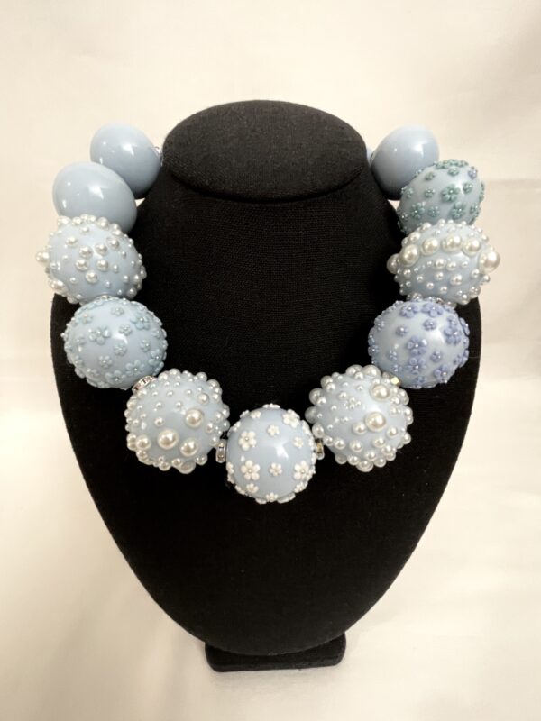 Extra large baby blue acrylic beads with miniature flowers and pearls.  The combination of the miniature flowers with the baby blue color softens the impact of the large beads.  It is a beautiful necklace with texture and color to admire.  The necklace measures 19IN/48CM/8oz, and it includes an extender.  This is a Carolina Liguori Original, only one made. 
