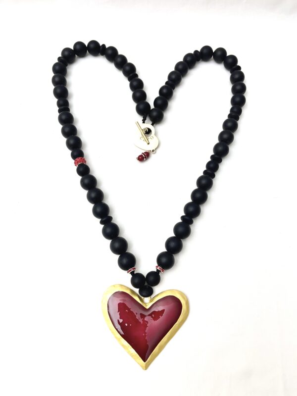 Long statement necklace made of black silicone beads with a large red heart pendant.  The necklace measures 33IN/84CM/6OZ.