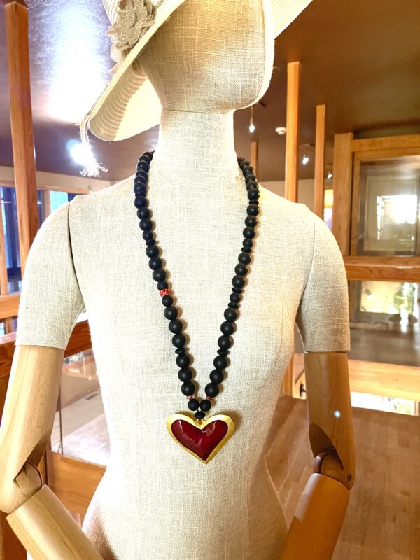 Long statement necklace made of black silicone beads with a large red heart pendant.  The necklace measures 33IN/84CM/6OZ.