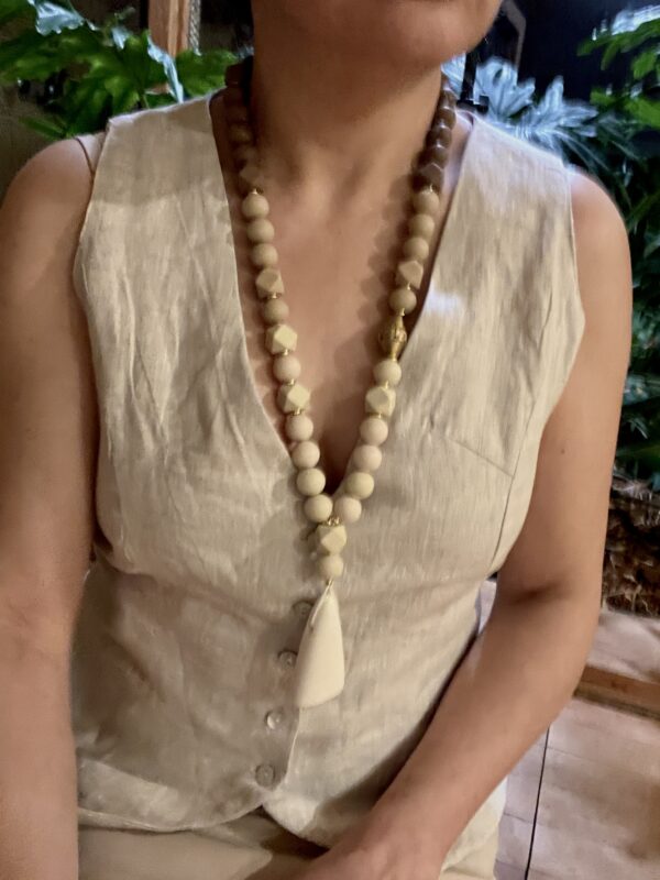 Long statement necklace made of cream and chocolate color silicone beads with a large irregular-shaped pendant.  Classic warm colors with gold accents.  Simple yet, elegant for everyday use and easy to travel with.  The necklace measures 28IN/8OZ.