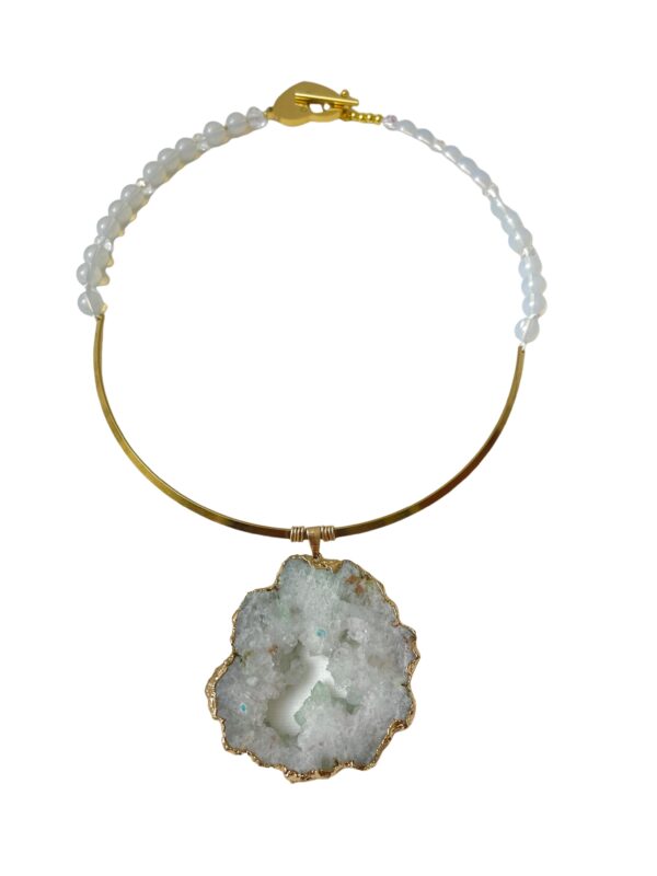 A sliced crystal rock on a gold frame with white beads.  Simple, yet dramatic.  It is a beautiful way to display the crystal in its natural state, a delicate look with a powerful meaning.  The necklace measures 24IN/6OZ