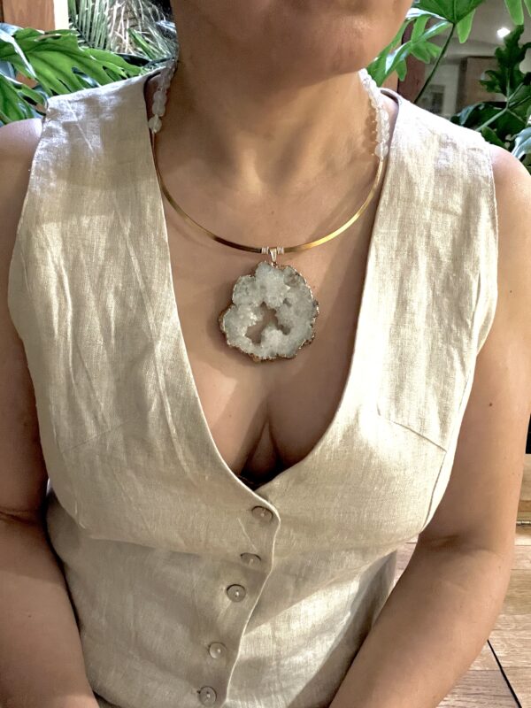 A sliced crystal rock on a gold frame with white beads.  Simple, yet dramatic.  It is a beautiful way to display the crystal in its natural state, a delicate look with a powerful meaning.  The necklace measures 24IN/6OZ