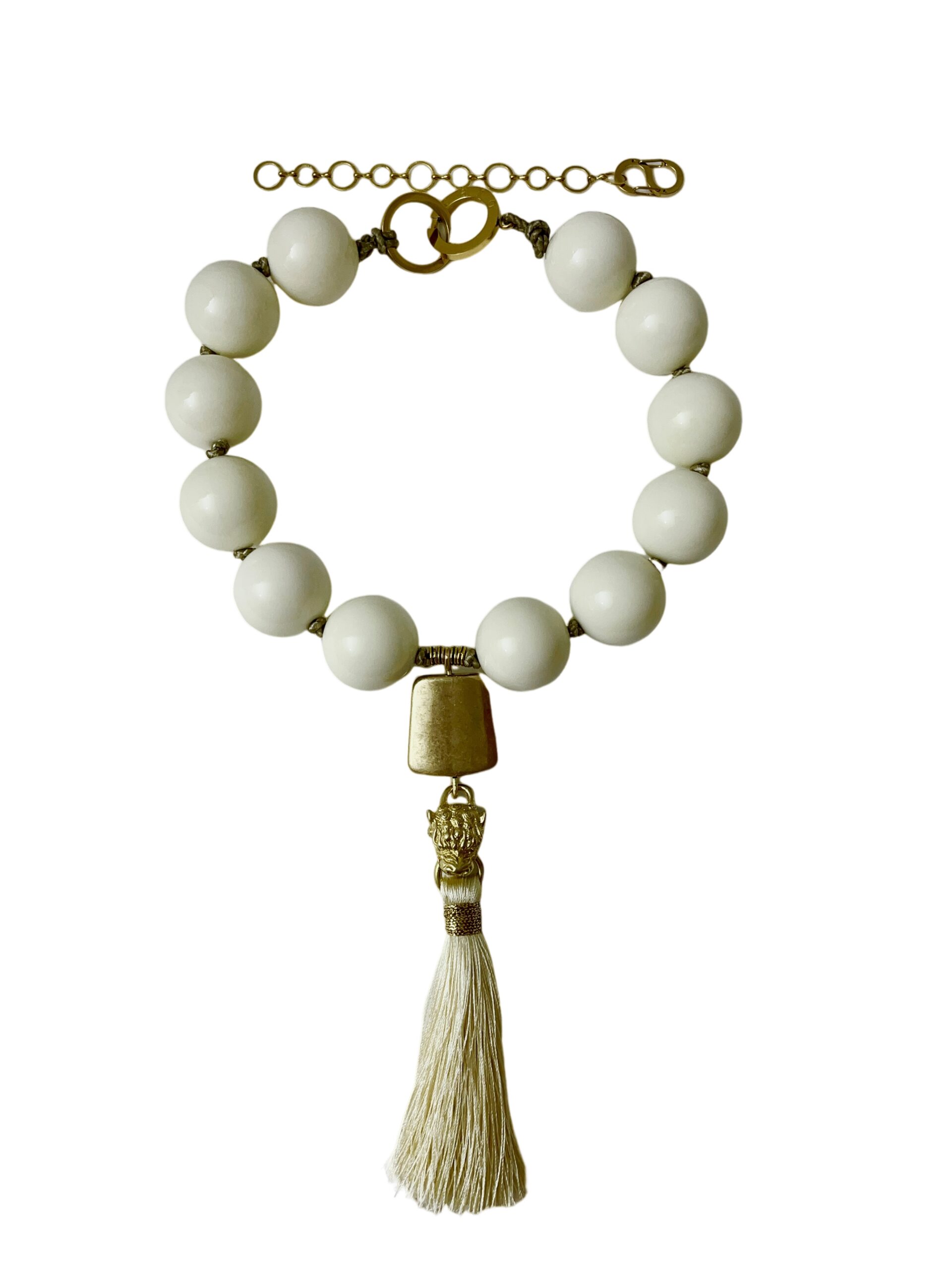 Statement necklace featuring large ivory beads with a gold accent pendant and a cream tassel. The design combines smooth spherical beads with metallic details for a refined, classic look.