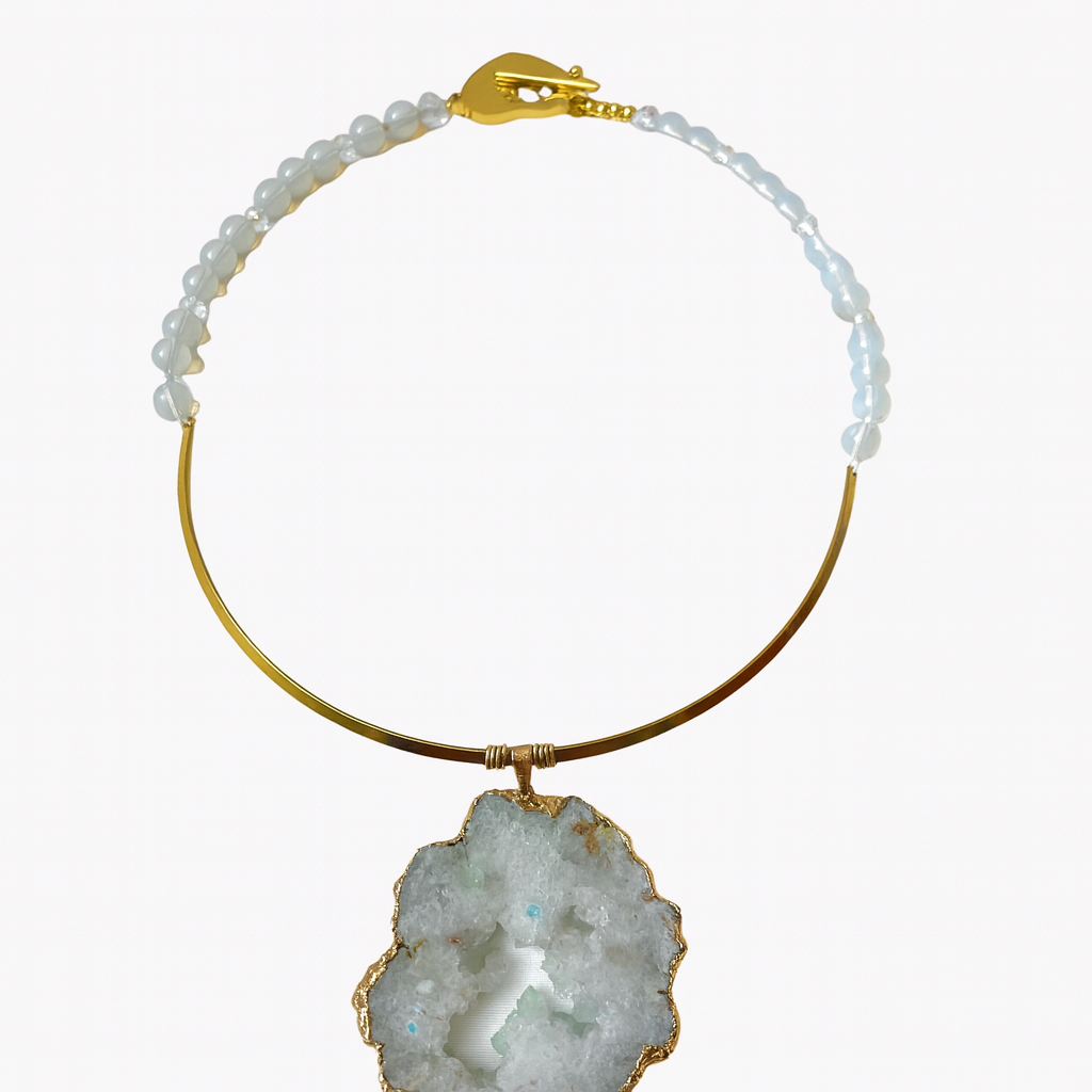 Elegant necklace featuring a large raw crystal slice pendant framed in gold. The upper section combines smooth white beads with a curved gold band, creating a refined balance between organic texture and polished metal.