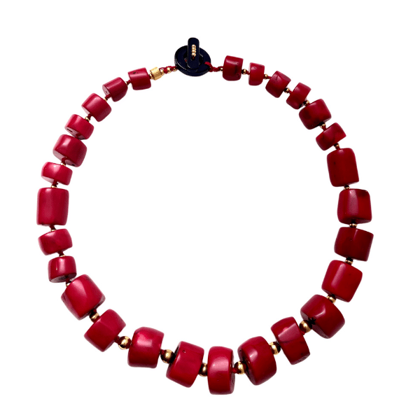 ❤️ Bold and radiant, the Coral Necklace is a handcrafted masterpiece that captures the essence of passion and purpose. Measuring just right for statement-making elegance, this exquisite piece features an arresting combination of natural, deep red coral beads—each expertly polished and sculpted into sleek cylindrical shapes. The rich color tones evoke a sense of vitality, warmth, and confidence, making it a standout accessory for day or night. A sophisticated black stone toggle clasp anchors the design with subtle contrast, balancing the fiery coral with understated refinement. The juxtaposition creates an alluring harmony that draws the eye and complements any wardrobe palette. More than just a stunning piece, the coral carries deep cultural and spiritual meaning. Revered for its ability to promote awakening and guide one toward a successful life, it has been worn throughout history as a symbol of strength and insight. This design is no coincidence—it reinforces the necklace’s fiery spirit and its energizing impact on both style and soul.  Wear the Coral Necklace as a personal emblem of bold beauty and inner empowerment. Let its color ignite your confidence and its craftsmanship speak to your story—striking, soulful, and distinctly you.
