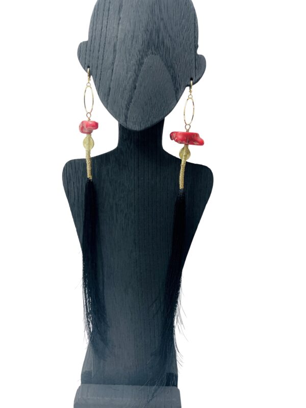 This pair of earrings is designed for those with long hair.  It is a playful combination of tassels, Coral, and Brass. The tassels are cut unevenly to mimic the natural shape of piggytails. The earrings are made of natural red coral with brass accent beads. They measure 12 IN/2 OZ.