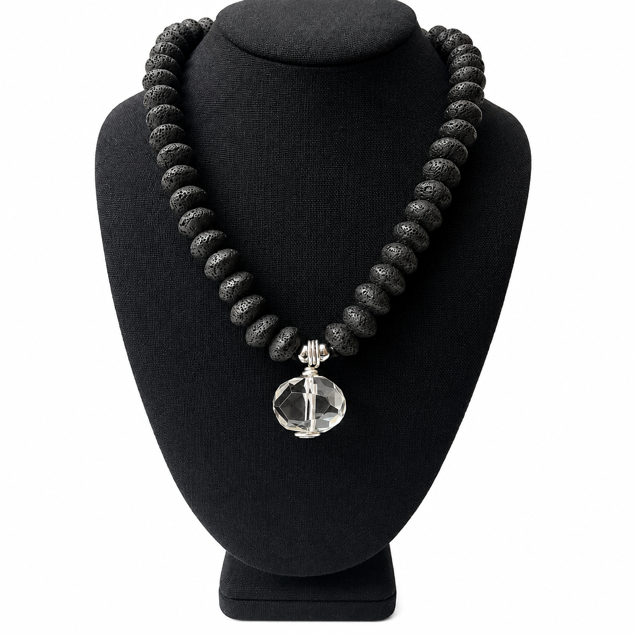 Necklace composed of matte black lava beads arranged in a display featuring a single faceted clear crystal pendant at the center. The clasp includes a silver chain extender for adjustable length.